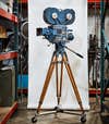 a vintage Technicolor camera standing up in an aisle of a camera museum in front of a photography backdrop